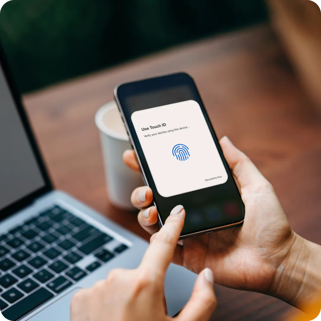 User holding phone with Duo Push screen displayed, enabling secure login through MFA.