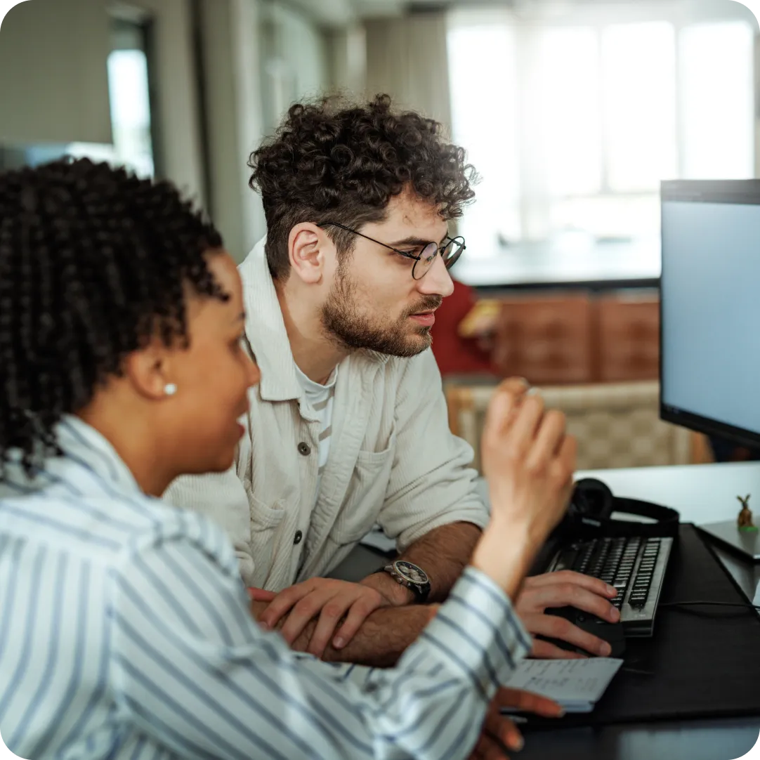 Two colleagues looking at desktop monitor that is showing the Cisco Partner Network.