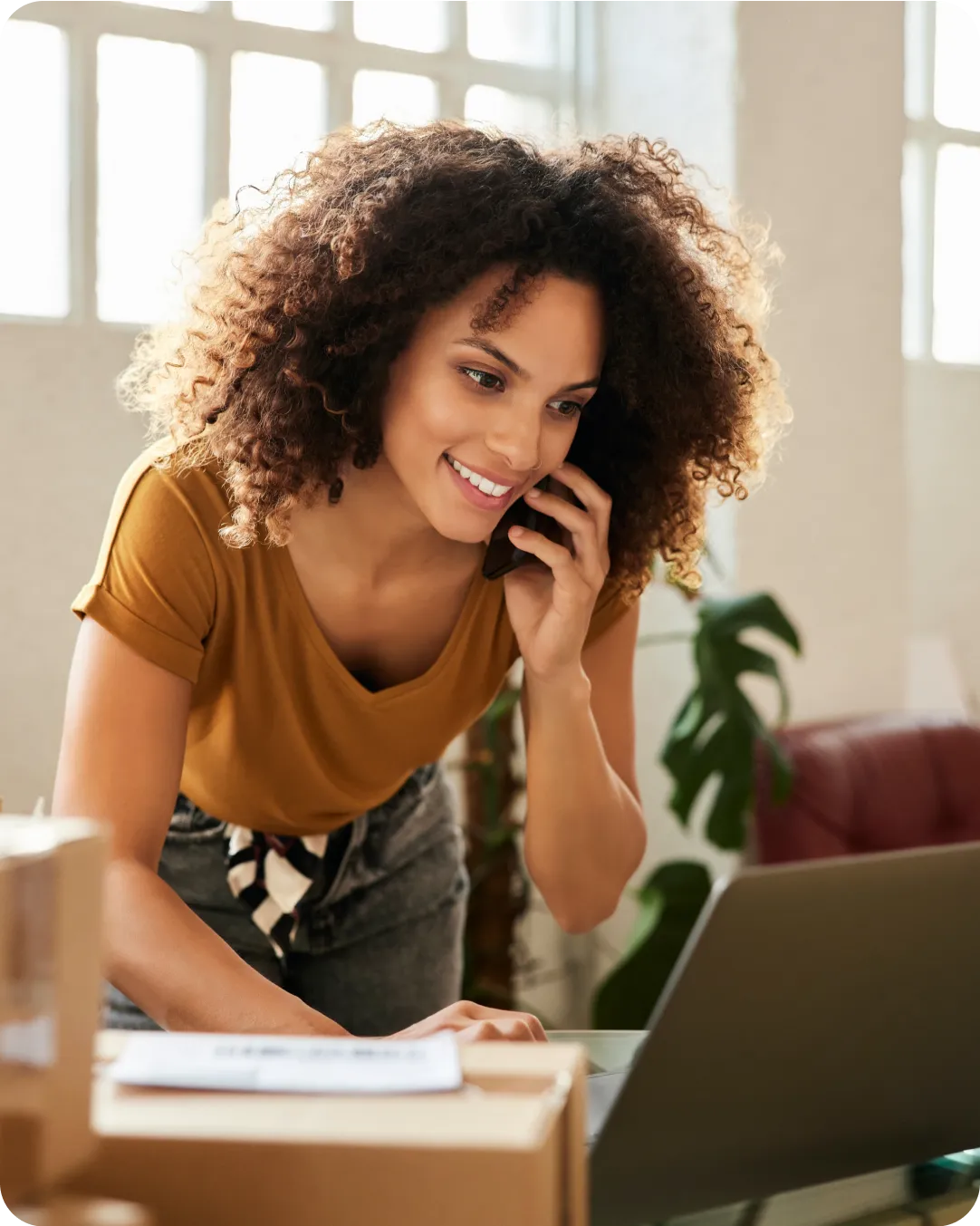 Business professional on the phone and looking at their laptop with a smile with Duo protecting their organization's operational alliance.