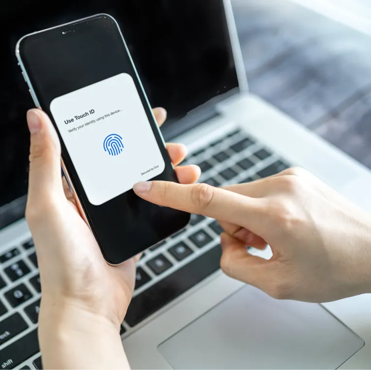 Closeup of a person holding a smartphone, they are using Duo's Touch ID to log in.