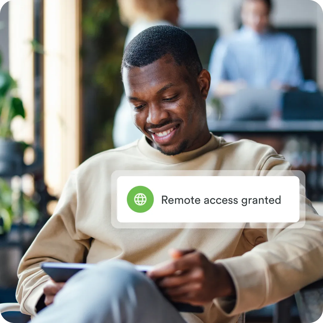 Professional developer on tablet smiling at it with a remote access push notification from Duo in the foreground indicating secure remote access.