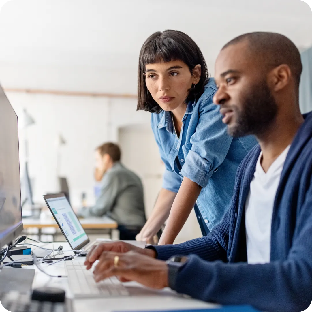 Two co-workers looking at a computer screen together to view Duo's other SaaS-security products in the Secure MSP Center.